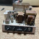 Fotografie znázorňuje otevřený elektronický přístroj v hnědém kovovém šasi s černým předním panelem. Na panelu jsou čtyři černé oválné ovladače a náp…