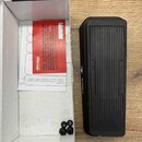 Černý kytarový pedál s nápisem AMPLIFIER na levém boku a logem 2-KICKER na pravém boku. Vedle pedálu je otevřená bílá krabice, ve které se nachází če…