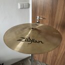 Kruhový mosazný činel umístěný na kovovém stojanu. Na povrchu je černý nápis Zildjian a v horní části menší text s logem. Povrch činelu vykazuje jemn…