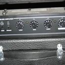 Zadní panel kytarového komba v černé barvě s nápisy V-TONE OM110 a ANALOG MODELING AMPLIFIER. Panel obsahuje ovládací prvky DRIVE, LOW, MID, HIGH a M…