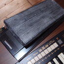 Černý expresní pedál značky HAMMOND s texturovaným, rýhovaným povrchem horní části. Na boku je vidět štítek s nápisy HAMMOND EXP-100, BASS TREBLE TON…