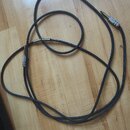 Černý instrumentální kabel s konektory typu jack. Na kovovém konektoru je vidět nápis "Sennheiser". Kabel vykazuje mírné známky používání a je polože…
