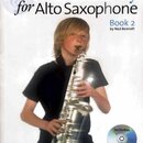 Fotografie znázorňuje obal učebnice s názvem A New Tune A Day for Alto Saxophone Book 2 by Ned Bennett. Na obálce je zobrazen mladý muž hrající na st…