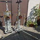 Na fotografii jsou dva kovové stříbrné stojany s mechanismem navijáku a žlutočernými varovnými pruhy. Na jednom ze stojanů je viditelný svislý nápis…
