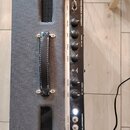 Kytarový kombozesilovač s černým texturovaným potahem a kovovým ovládacím panelem. Na panelu jsou nápisy FENDER MUSICAL INSTRUMENTS, CHANNEL ONE / 20…