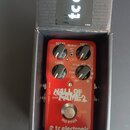 Červený efekt pedál v kartonové krabici s nápisem tc electronic. Na zařízení jsou nápisy tc electronic, TRUE BYPASS, HALL OF FAME 2, REVERB, STEREO O…