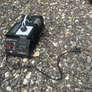 Černý kouřový stroj s nápisem M-Fog 1000 Smoke Fog Machine. Zařízení má ovládací panel s přepínači, dvěma červenými kontrolkami a konektory pro napáj…