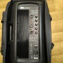 Černý zesilovač v černé transportní tašce. Na horním panelu jsou nápisy R1 Power Dynamics, PDE-12A a 1000W, dále ovládací prvky pro Volume, Treble a…