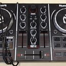 Černý DJ kontrolér značky Numark s modelem PARTY MIX. Zařízení má dva stříbrno-černé jog-wheels, středovou sekci s knoflíky a posuvníky a spodní část…