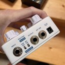 Bílý efekt pedál s několika ovládacími prvky a konektory. Na spodní straně jsou nápisy INPUT, ROUTING MUTEX, OUTPUT, EXT.SW a DC 9V spolu s přepínači…