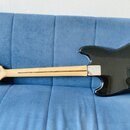 Zadní strana elektrické basy s černým lesklým korpusem a světlým javorovým hnedem krku. Na zadní části hlavy je vidět nápis Fender. Nástroj má čtyři…