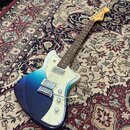 Elektrická kytara s modro-bílým přechodem barvy (burst) a bílým pickguardem. Na hlavě hmatníku je viditelné logo Fender. Nástroj má dva snímače, tři…