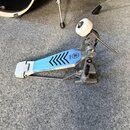 Kovový basový pedál s modrým šlapadlem. Na šlapadle je umístěno logo Yamaha a černý grafický vzor z šipek. Pedál vykazuje známky používání v podobě d…