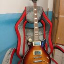 Elektrická kytara typu Les Paul s barevným přechodem od žluté k tmavě hnědé. Na hlavě hmatníku je bílý nápis Harley Benton. Nástroj má dva humbuckery…