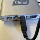 Stříbrné audio rozhraní s nápisy U24XL a logem esi. Na předním panelu jsou konektory s označením OUT (COAXIAL), IN, USB, OUT (OPTICAL) a IN. Do USB p…