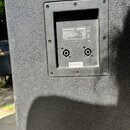 Detail zadní strany černého reproduktoru s texturovaným povrchem. V zapuštěném panelu je štítek s nápisy KEMPTON PW 215, CE a technickými specifikace…