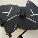 Dvě černé plastové krycí kryty s bílými nápisy beyerdynamic a bílým grafickým symbolem ve tvaru písmene Y. K krytům jsou připojeny dva malé černé ada…