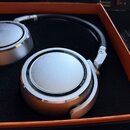 Stříbrná studiová sluchátka v oranžovém originálním boxu s černou vložkou. Na pravém sluchátku je nápis NEUMANN BERLIN a STUDIO HEADPHONE KH 80. Povr…
