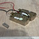 Dva kovové snímače k elektrické kytáře s připojenými červeným a černým vodičem. Na obou snímačích jsou bílé samopřilépené štítky s nápisem „SUCHEOI D…