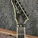 Hlava elektrické kytary s černým povrchem a bílým lemováním. Na čele je bílý nápis "B.C. Rich" a pod ním vertikální text "WARLOCK NJ DLX". Jsou vidět…