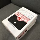 Bílá papírová krabice s nápisy electro-harmonix a BIG MUFF. Na horní straně je znázorněn efekt s ovládacími prvky VOLUME, TONE, SUSTAIN a konektory A…