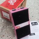 Růžový efekt pedál s černými texturovanými plochami. Na krabici je nápis JHS PEDALS, LUCKY CAT DELAY a SERIAL# 3250. Na samotném pedálu je viditelné…
