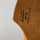 Záběr na zadní stranu dřevěné hlavy kytary v přirozené barvě. Je zde uveden nápis Designed and Backed by Fender®, sériové číslo s/n ISS822010989 a te…