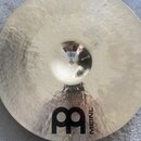Zlatý kovový činel s viditelným broušením povrchu. V dolní části je černý nápis MEINL a velké logo ve tvaru stylizovaného písmene B. U středu činelu…