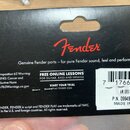 Záběr na zadní stranu černého papírového obalu s červeným logem Fender. Pod logem je nápis „Genuine Fender parts – for pure Fender sound, feel and pe…