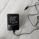Černý plastový AC/DC adaptér s připevněným kabelem. Na štítku je uveden název electro-harmonix a nápisy: AC/DC ADAPTOR, PART NO. EU8 600-230, MODEL:…