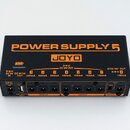 Černý napájecí adaptér s oranžovými nápisy a logem JOYO. Na horní straně je velký nápis POWER SUPPLY 5 a označení výstupů DC 9V OUT s čísly 1 až 8. P…