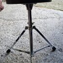 Černý kulatý sedák z koženky na chromovaném třínohém stojanu. Stojan má nastavitelnou výšku a kovové rozpěrné vzpěry. Na předmětu nejsou vidět žádné…