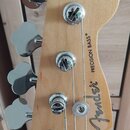 Hlava basové kytary z přírodního světlého dřeva s čtyřmi chromovanými ladičkami. Na povrchu je černý nápis Fender® a PRECISION BASS®. Povrch dřeva je…