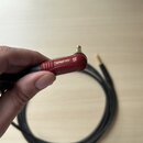 Černý audio kabel s červeným konektorem typu jack. Na červené části konektoru jsou vyraženy nápisy SILENT a NEUTRIK. Kabel je svinutý do kruhu na svě…