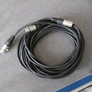 Černý audio kabel svlnutý do kruhu, zakončený dvěma stříbrnými konektory XLR. Na povrchu kabelu je opakovaně bílý nápis PROFESSIONAL CABLE a ROCKCABL…