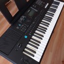 Černý digitální klavír s bílými a černými klávesami. Na horním panelu je nápis PSR-E373 a logo YAMAHA u displeje. Nástroj obsahuje řadu tlačítek, pos…
