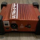Kovová červená krabička s nápisy BEHRINGER a ULTRA-G. Na horní straně je text ACTIVE DI-BOX/VIRTUAL 4x12" CABINET SIMULATION MODEL G100. Zadní panel…