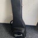 Černý polotvrdý obal na kytaru z materiálu s texturou kůže. V dolní části je bílý nápis Gibson v charakterickém písmu. Obal má na pravé straně kovový…