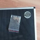 Detailní pohled na černý transportní case s hliníkovým profilem. Na povrchu je nalepený kulatý štít s nápisy Custom-made, MusicData CASES & STUDIO FU…