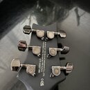 Záběr na zadní stranu hlavy elektrokitary v matně černé barvě s šesti chromovanými ladičkami. Na krytkách ladiček je vyryto logo PRS a na zadní stran…