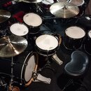 Černá bicí souprava s bílými blanami. Na blanách jsou vidět loga EVANS a nápisy Mapex. Souprava obsahuje basový buben, několik tomů, malý buben a tři…