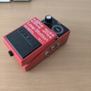 Červený efekt pedál s černým spínacím pedalem a ovládacím knoflíkem. Na horní části je bílý nápis Loop Station a model RC-1, vlevo logo BOSS. Jsou zd…