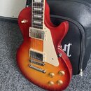 Elektrická kytara s tmelem v červeno-žlutém sunburst provedení a bílým pickguardem. Nástroj má dva humbuckery s krémovými rámečky, čtyři zlaté ovláda…