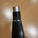 Detailní pohled na hnedý, pravděpodobně plastový nebo lakovaný nástroj s kovovým houthoutem v horní části. Mezi kovovou částí a tělem je černý krouže…