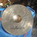 Kruhový činel z kovu s viditelným broušením povrchu. Na spodní části je černý nápis „alchemy cymbals“ a v horní části malý nápis „by ISTANBUL AGOP“.…