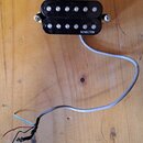 Černý humbucker s dvěma řadami bílých pólů, upevněný dvěma šrouby po stranách. Na spodní pravé části je bílý nápis SCHECTER. Z pickupu vede šedý kabe…