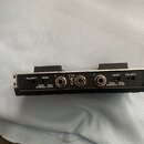 Fotografie znázorňuje zadní stranu černého elektronického zařízení s kovovým panelem. Na panelu jsou dva přepínače s nápisy POLARITY a MODE, tři jack…