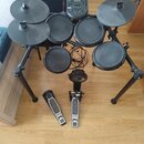 Elektronická bicí souprava černé barvy na kovovém stojanu. Na ovládacím modulu je nápis ALESIS a vedle něj označení NITRO. Souprava obsahuje pět padů…