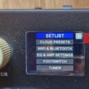 Detailní pohled na ovládací panel černého elektronického zařízení. Je zde vidět bílý žebrovaný oválkový knoflík s nápisem MASTER a displej s menu, kd…