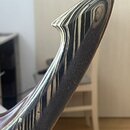 Detail hlavy strunového nástroje s černobílým pruhovaným vzorem. Povrch je lesklý, v horní části je viditelný jeden ladicí kolík. Na nástroji nejsou…